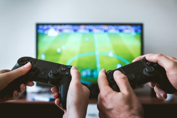 2 game controles achter scherm met voetbalspel