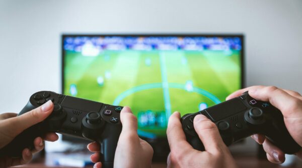 2 game controles achter scherm met voetbalspel