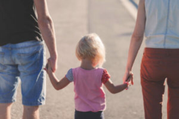 Blond meisje van 3 jaar loop in het midden hand in hand met vader en moeder.