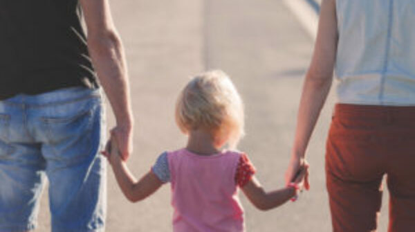 Blond meisje van 3 jaar loop in het midden hand in hand met vader en moeder.