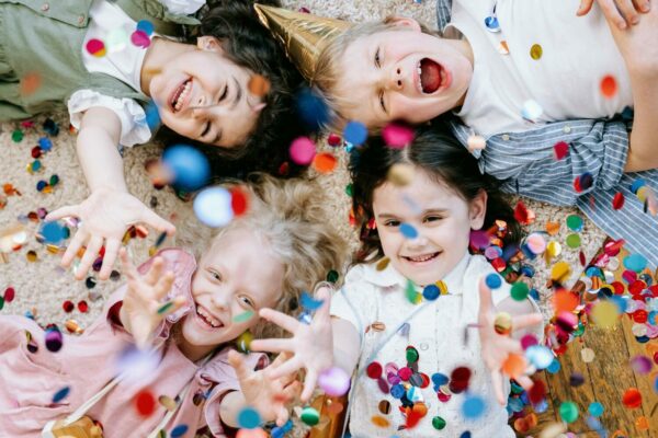 Vier kinderen liggend op de grond die confetti in de lucht gooien